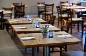 a row of wooden tables with glasses and flowers on them at DoubleTree by Hilton Swindon Hotel in Swindon