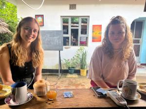 two women sitting at a wooden table with coffee at Meleji studio room in Arusha