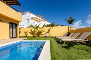 a villa with a swimming pool and lounge chairs at VILLA WITH 4 BEDROOMS AND PRIVATE HEATED POOL in San Miguel de Abona