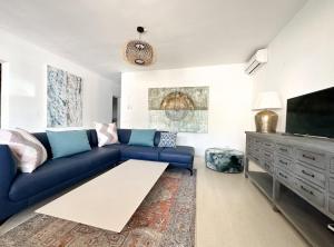 sala de estar con sofá azul y TV de pantalla plana en Villa Colibrí, con piscina privada para 6 personas, en Santa Ponsa