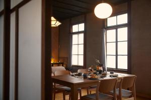 uma sala de jantar com mesa, cadeiras e janelas em Lhotel de Mai em Tamba-sasayama