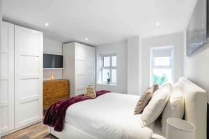 - une chambre blanche avec un grand lit et une commode dans l'établissement Luxury 1 bed apartment - Wanstead Village, à Londres