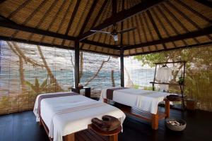 two beds in a room with a large window at Alila Manggis in Candidasa