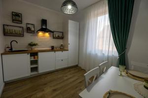 a kitchen with white cabinets and a table and a window at Cozy Studio in Sibiu +8 photos