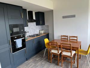 a kitchen with blue cabinets and a wooden table and chairs at Pentyla by StayStaycations in Port Talbot