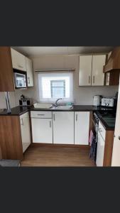 a small kitchen with white cabinets and a window at Jules Holiday Caravan in Hartley