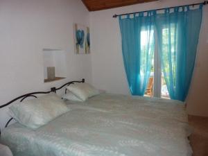 a bedroom with a bed with blue curtains and a window at Nikatsas Cottage No 1 in (( Kerasá ))