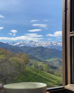 una ventana con vistas a las montañas cubiertas de nieve en La Montaña Mágica Hotel Rural en Vibaño