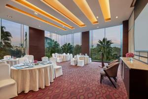 une salle de banquet avec des tables blanches, des chaises et des fenêtres dans l'établissement DoubleTree by Hilton Gurugram Baani Square, à Gurgaon