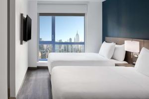 ニューヨークにあるHyatt Place NYC Chelseaのベッド2台と大きな窓が備わるホテルルームです。