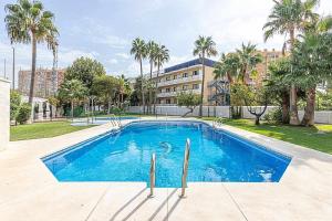 a large swimming pool with palm trees and a building at 797 Holiday Rentals - Luminoso piso para 4 en Arroyo de la miel in Arroyo de la Miel