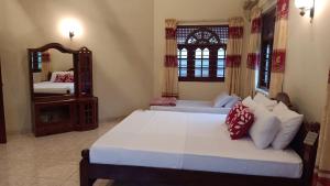 a bedroom with two beds and a mirror at Osh villa in Hikkaduwa