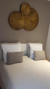 a white bed with two pillows and two plates on the wall at Saint-Cosme Home in Chalon-sur-Saône