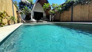 a swimming pool with blue water in front of a house at 3 Angels One-Bedroom Villa in Gili Islands