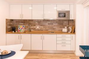 エリセイラにあるGrandchildren Loft by Ericeira Propertyの白いキャビネットと電子レンジを備えたキッチン