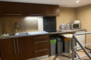 Una cocina con armarios de madera, fregadero y microondas. en Kwatera Kryształowa, en Poniec