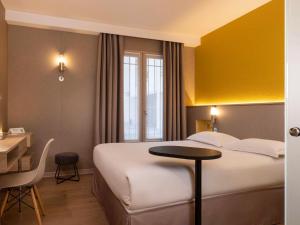 Pokój hotelowy z łóżkiem, stołem i biurkiem w obiekcie ibis Styles Bourg La Reine w mieście Bourg-la-Reine