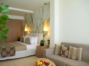 a hotel room with a bed and a couch at The Ixian Grand & All Suites - Adults Only Hotel in Ixia