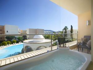 a bath tub with a view of a pool at The Ixian Grand & All Suites - Adults Only Hotel in Ixia