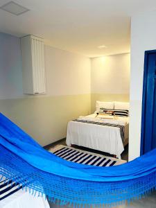 a bedroom with two beds and a blue hammock at Casa Grécia Pousada in Santo Amaro