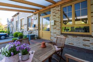 eine Terrasse mit einem Holztisch mit 2 Stühlen und Blumen in der Unterkunft Gästehaus Hansen in Wees