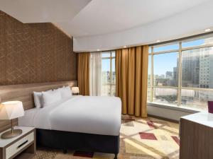 a bedroom with a large bed and a large window at Mercure Makkah Aziziah in Makkah