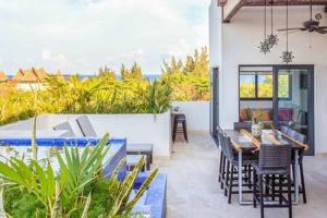 eine Terrasse mit einem Tisch, Stühlen und einem Pool in der Unterkunft Gorgeous Private Pool with Terrace Steps to Beach and 5th Ave! in Playa del Carmen