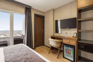 um quarto de hotel com uma cama, uma secretária e uma televisão em Operla Airport Hotels, Trademark Collection by Wyndham em Arnavutköy