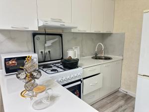 Una cocina blanca con estufa y fregadero. en Kojomkul, en Bishkek 11 fotos más