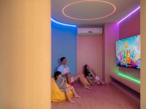 un grupo de personas sentadas en una habitación viendo televisión en Novotel Living Bangkok Sukhumvit Legacy en Bangkok
