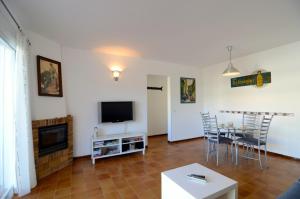 sala de estar con TV, mesa y sillas en Apartamento Mar Blau II, en Begur