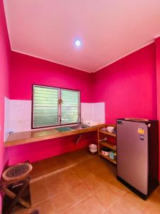 a kitchen with pink walls and a window and a refrigerator at Mandala bungalow at Ya Nui beach in Rawai Beach