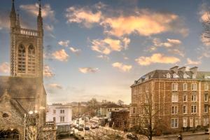 ブリストルにあるModern Spitfire with FREE PARKING by Prescott Apartmentsの曇り空に映える教会の尖塔と建物