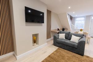 a living room with a couch and a television on a wall at Newly Renovated Family and Workspace Business Home in Runcorn, Cheshire ENTIRE HOUSE 