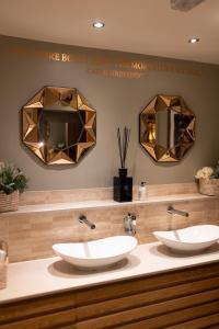 twee wastafels in een badkamer met twee spiegels bij The Dog in Over Peover in Knutsford