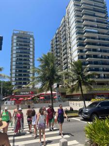 a group of people walking across a street with buildings at BarraBella Apartamentos in Rio de Janeiro