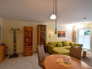 ein Wohnzimmer mit einem grünen Sofa und einem Tisch in der Unterkunft Ferienwohnung 9 im Seeschloss Binz - nur 50 Meter bis zum Strand in Binz