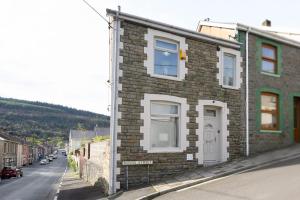 um edifício de tijolos ao lado de uma rua em Poet's Cottage by StayStaycations em Aberdare