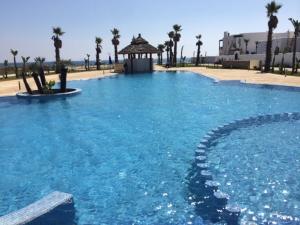 a large swimming pool with a gazebo and palm trees at Apartment Cabo Negro Royal Golf and Resort in Cabo Negro