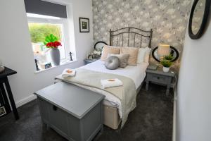 Un dormitorio con una cama grande y una ventana en Poet's Cottage by StayStaycations en Aberdare