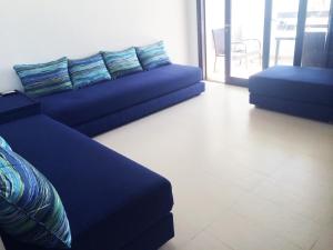 a living room with a blue couch and a balcony at Apartment Cabo Negro Royal Golf and Resort in Cabo Negro