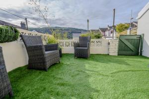a yard with three chairs and a green door at Poet's Cottage Wonderful Cottage In The Welsh Valleys by STAE-Homes in Aberdare