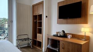 a hotel room with a bed and a desk with a television at Hotel Carlton Nice, Partially Renovated in Nice