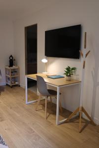 una scrivania con sedia e una TV appesa a un muro di Le Clos Doré - appartement et Spa a Chessy