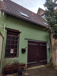 Casa verde con puerta de madera y ventana en Ferienwohnung am Stadtgarten, en Meisenheim