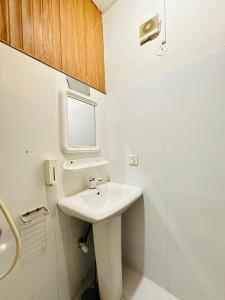 uma casa de banho branca com um lavatório e um espelho em Hotel SeaView 2 em Karachi