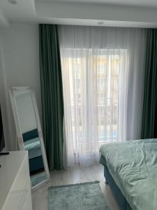 a bedroom with a mirror and a bed with green curtains at Adagio apartment in Creţuleasca +35 photos