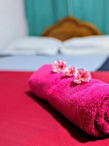 a pink towel with flowers on top of a bed at Udawalawa Safari House in Udawalawe