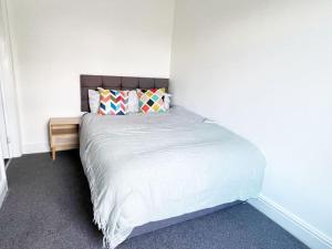 een slaapkamer met een wit bed en een houten nachtkastje bij Failsworth, Manchester in Manchester