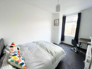 een slaapkamer met een bed, een bureau en een raam bij Failsworth, Manchester in Manchester